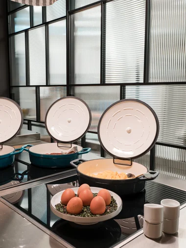 Drei offene Töpfe mit Essen und eine Schale mit Eiern auf einer modernen Küchentheke