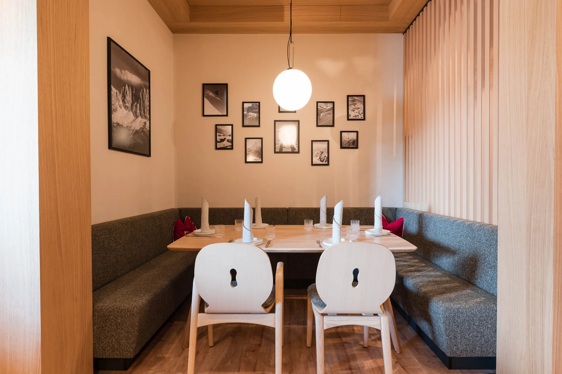 Cervus: the restaurant in Königsbrunn with special flair Kleine Sitznische im Restaurant Cervus mit gedecktem Tisch, Sitzbänken, Stühlen, Wandbildern und warmem Licht.