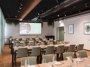 Zeller’s Quartier: das besondere Tagungshotel in Bayern Moderner Veranstaltungsraum mit gedeckten Tischen und Projektor an der Decke