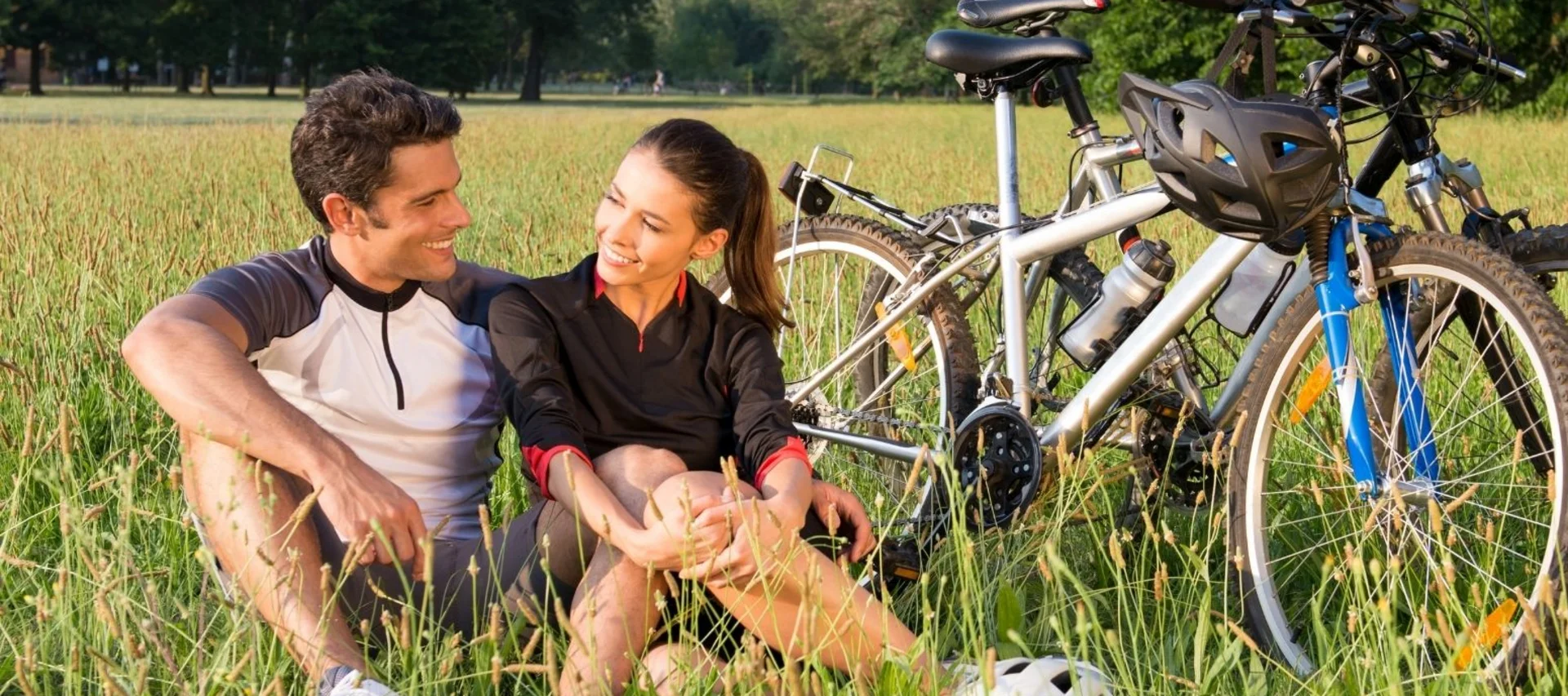 Unsere liebsten Fahrradtouren rund um Königsbrunn – Radfahren bei Augsburg beginnt direkt vor der Tür Paar sitzt auf einer Wiese neben Fahrrädern an einem sonnigen Tag