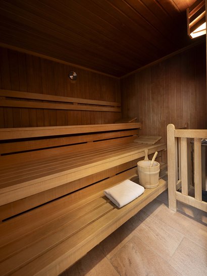 Ihr besonderes Hotel in Königsbrunn: Zeller’s Quartier Leere Holzsauna mit Handtuch und Saunakübel mit Löffeln