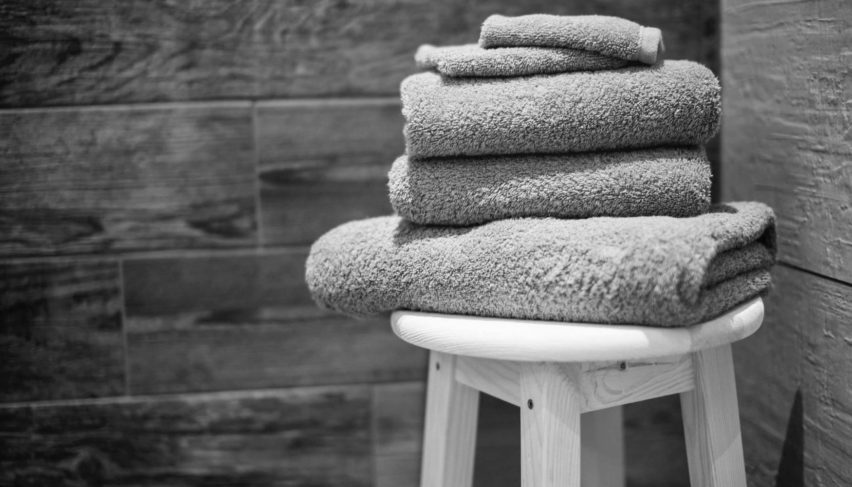 Hotel with sauna in Bavaria: Zeller’s Quartier Folded towels on a stool against a wood-paneled wall