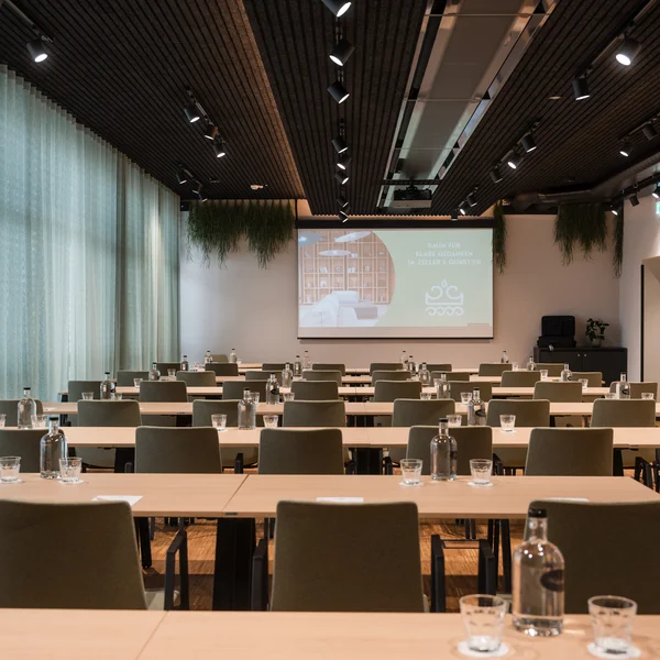 Helles Seminarzimmer mit grünen Stühlen und grünen Vorhängen