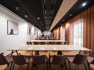 Zeller’s Quartier: das besondere Tagungshotel in Bayern Moderner Konferenzraum mit Tischen, Stühlen und orangefarbenen Vorhängen
