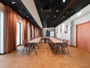 Zeller’s Quartier: das besondere Tagungshotel in Bayern Moderner Konferenzraum mit U-förmigen Tischen und orangen Vorhängen