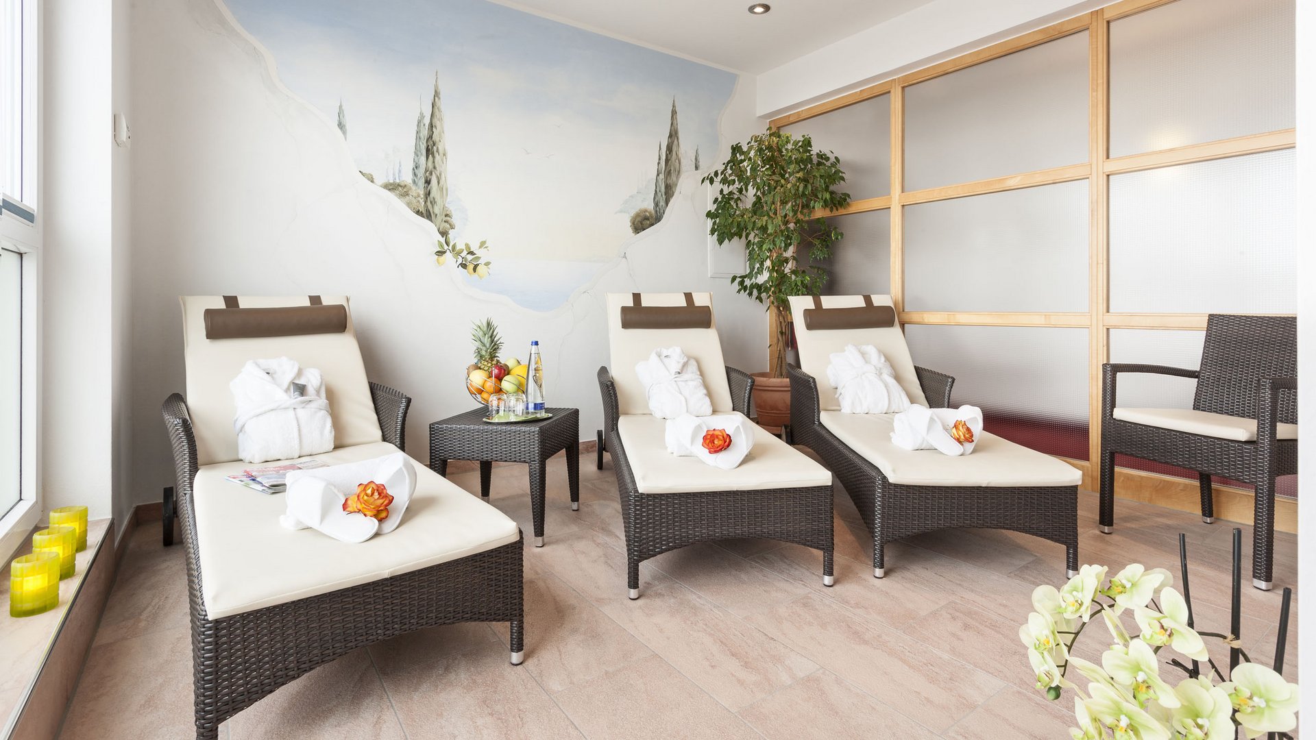 Relaxation room with loungers, bathrobes, fruit bowl, and wall mural