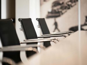 Leere schwarze Bürostühle neben einem weißen Konferenztisch