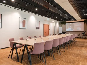Zeller’s Quartier: das besondere Tagungshotel in Bayern Moderner Konferenzraum mit langem Tisch, rosa Stühlen und Leinwand