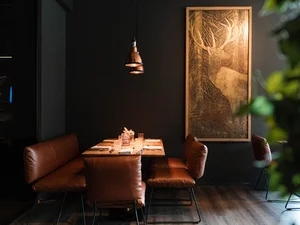 Tisch in der Südtiroler Stube Gedeckter Tisch mit brauner Sitzbank in stimmungsvoll beleuchtetem Restaurantbereich des Cervus.