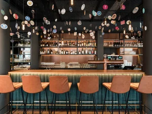 Cervus Bar Bar im Restaurant Cervus mit langer Holztheke, braunen Barhockern, beleuchtetem Spirituosenregal und dekorativer Deckenbeleuchtung.