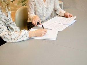 Zwei Frauen in gepunkteten Blusen bei der Arbeit mit Dokumenten am Tisch