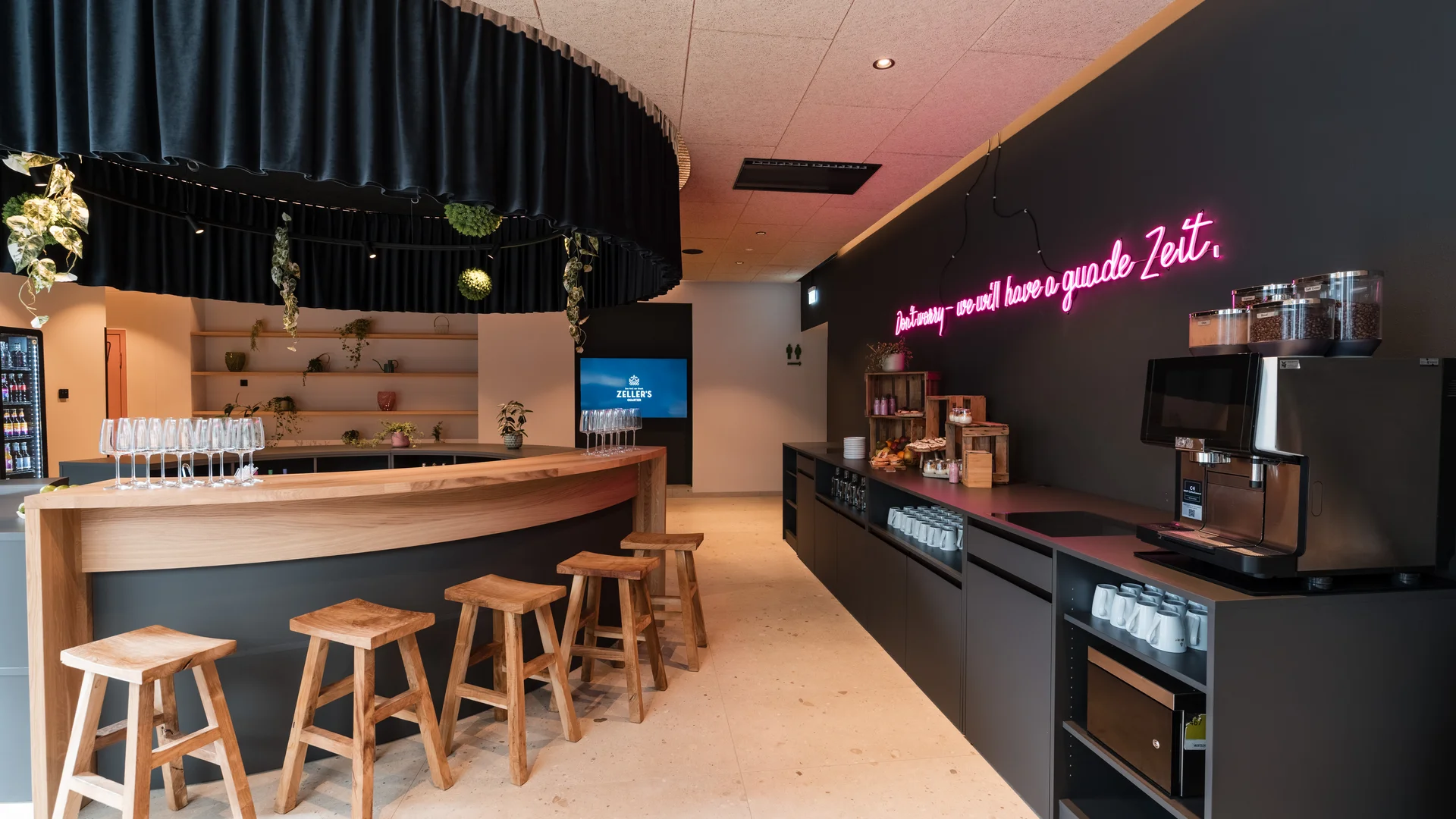 Das besondere Tagungshotel in Bayern Modernes Tagungsbuffet in einem stilvollen Tagungsbereich mit dunklem Design, Buffetinsel und beleuchtetem Schriftzug an der Wand.
