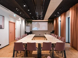 Zeller’s Quartier: das besondere Tagungshotel in Bayern Moderner Konferenzraum mit U-förmigen Tischen, rosa Stühlen und Projektionsleinwand