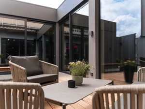 Loungesitzgruppe auf der Terrasse Lounge-Sitzgruppe mit Tisch und Pflanzen auf der Holzterrasse im Innenhof des Zeller’s Quartier. SEO-Alternative: