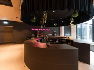 Zeller’s Quartier: das besondere Tagungshotel in Bayern Runder Barbereich mit Pflanzen und schwarzem Vorhang im modernen Innenraum