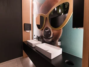 Waschbecken in der Toilette Moderne Lobby-Toilette im Zeller’s Quartier mit zwei Waschbecken, rundem Spiegel und auffälligem Wandmotiv.