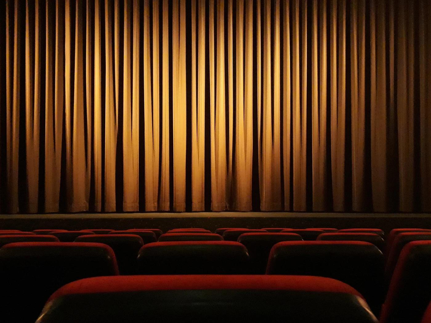 Theatre with closed curtains and red seats. Theatre with closed curtains and red seats.