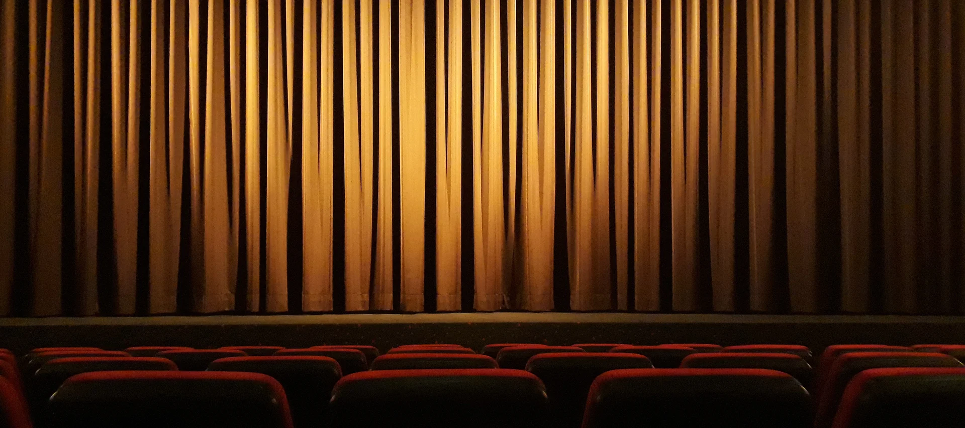 Theatre with closed curtains and red seats. Theatre with closed curtains and red seats.