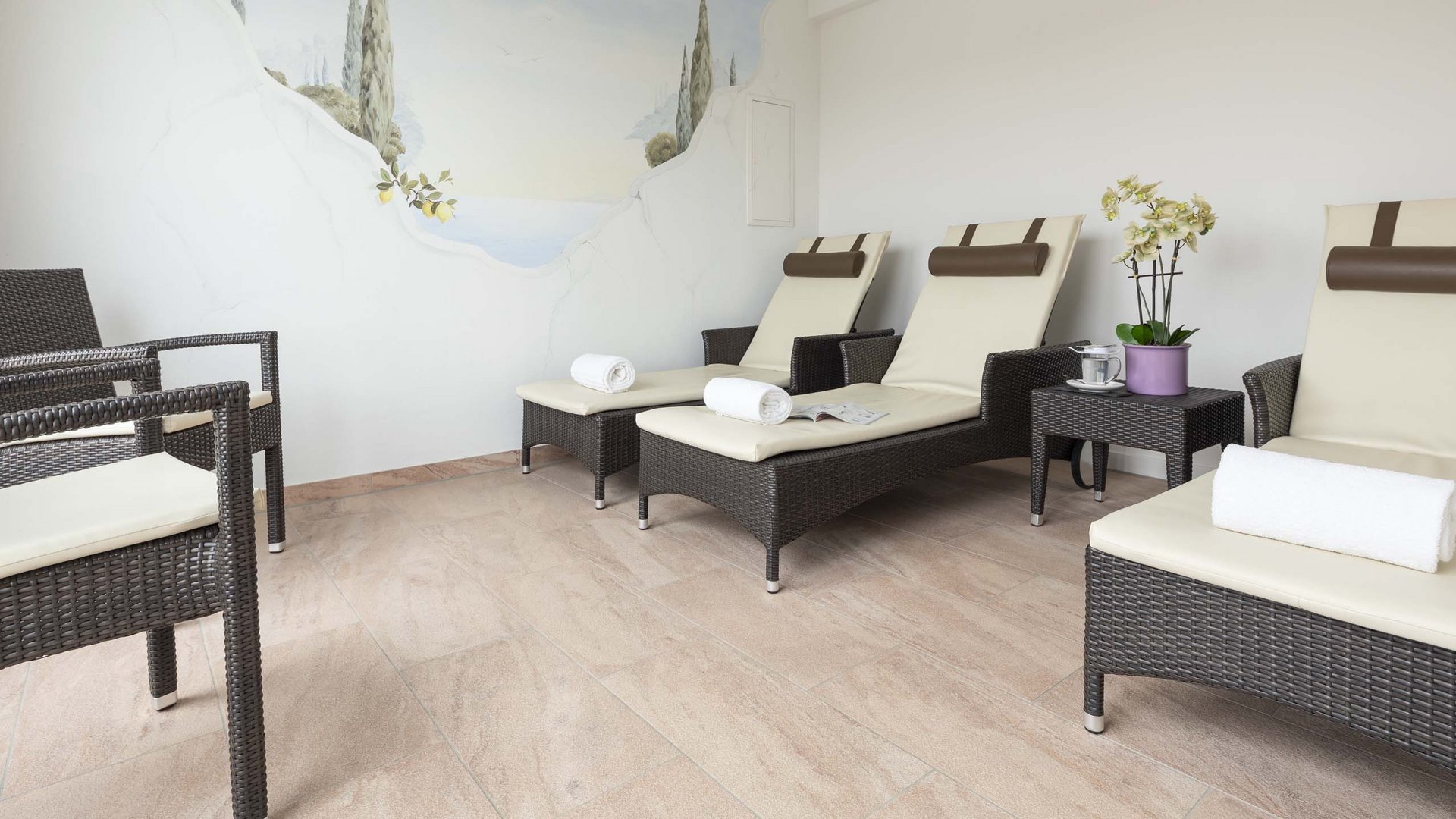 Relaxation room with lounge chairs and mural of a Mediterranean landscape