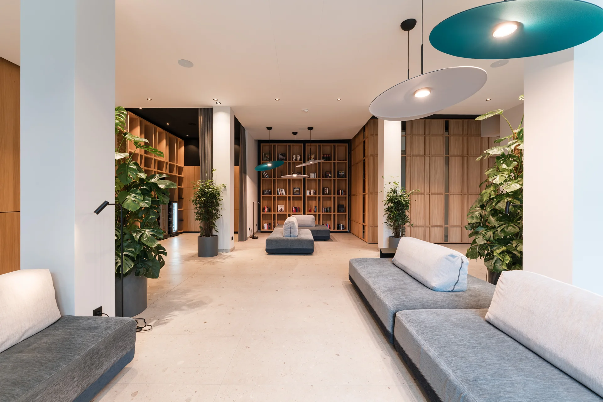 Moderner Wartebereich mit Sofas, Pflanzen und Bücherregalen