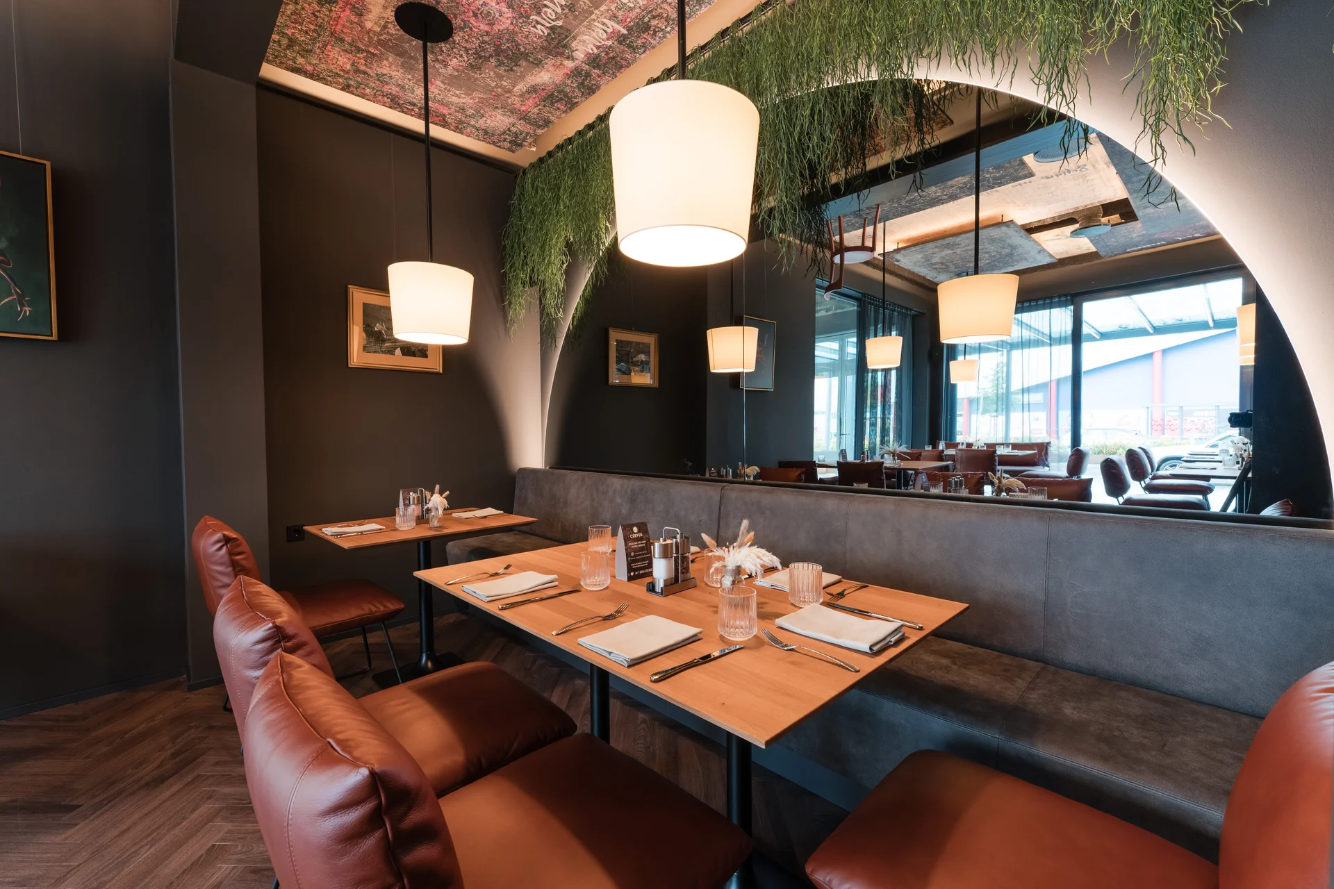 Modern eingerichtetes Restaurant mit Ledersesseln und hängenden Lampen
