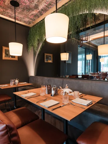 Modern eingerichtetes Restaurant mit Ledersesseln und hängenden Lampen