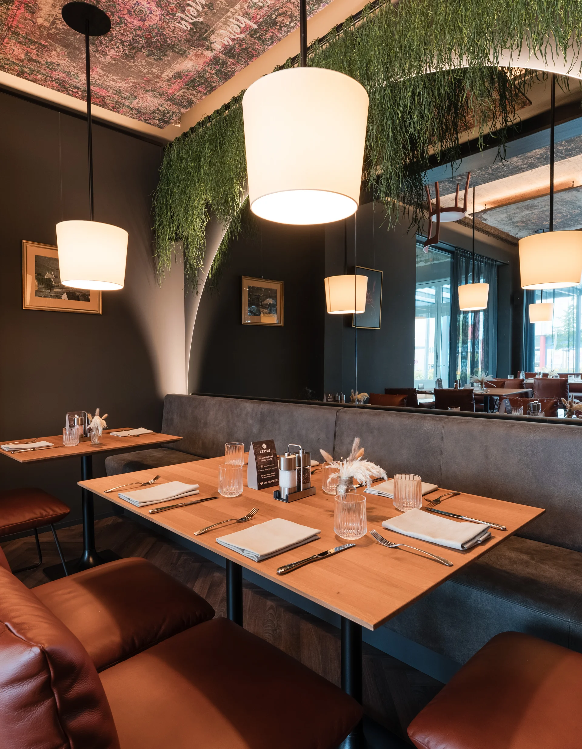 Modern eingerichtetes Restaurant mit Ledersesseln und hängenden Lampen