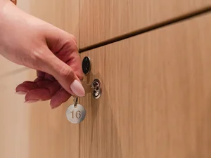 Schließfach im Zeller´s Quartier Hand schließt ein Holzschließfach mit Schlüssel und nummeriertem Anhänger im Zeller’s Quartier ab.