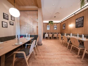 Südtiroler Stube Langer Gastraum im Restaurant Cervus mit gedeckten Holztischen, Sitzbänken, Stühlen, Holzverkleidung und warmem Licht.