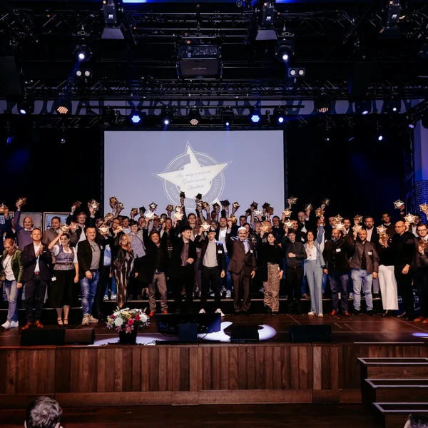 Gruppenfoto der Gewinnerinnen und Gewinner der Goldener Stern Award Verleihung auf der Bühne im Paulaner am Nockherberg in München. Alle halten ihre Trophäen hoch, im Hintergrund ist eine große Leinwand mit dem Award-Logo zu sehen.“
