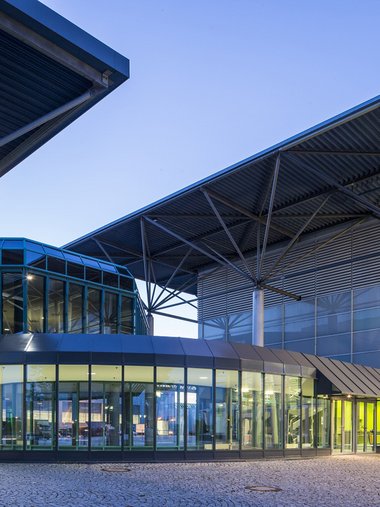 Moderne Glas- und Stahlgebäude bei Dämmerung mit beleuchteten Innenräumen