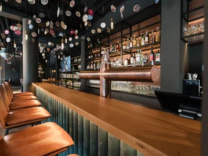 Cervus Bar Lange Holzbar mit Lederhockern und beleuchtetem Rückbuffet im Restaurant Cervus.