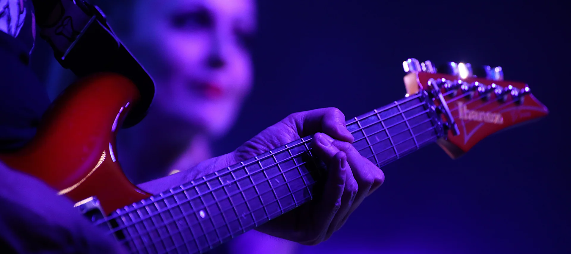 Voxxclub - 7. EHC Schlager-Night Close-up of a person playing an electric guitar under purple stage lighting