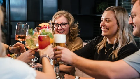 Gruppe von Freunden stößt mit verschiedenen Getränken an und lächelt