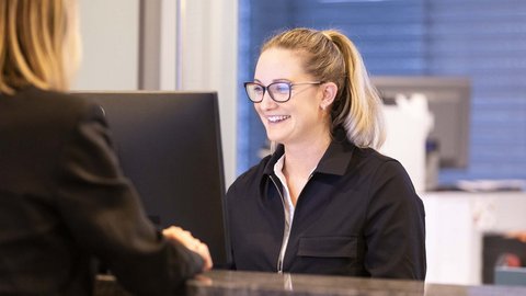 Lächelnde Empfangsdame am Schreibtisch bei der Arbeit