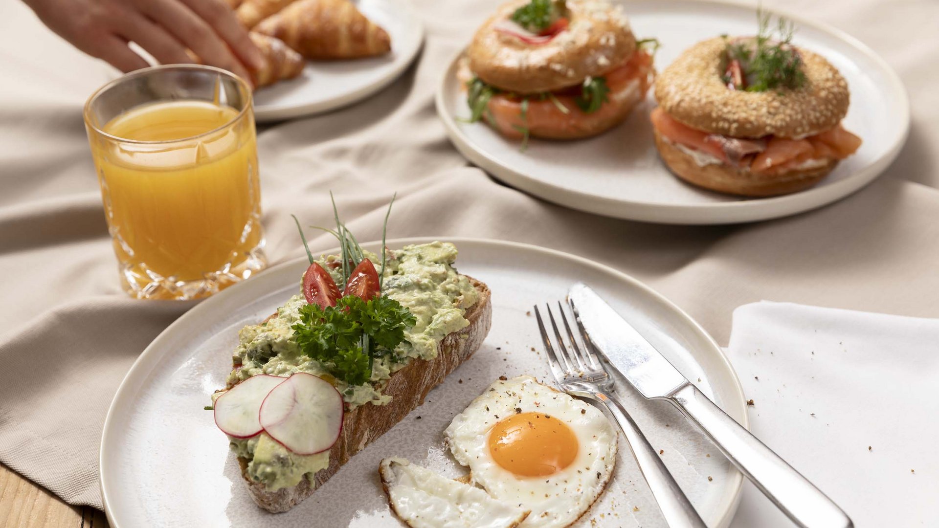 Frühstück mit Rührei, belegtem Brot, Lachs-Bagels, Croissants und Orangensaft