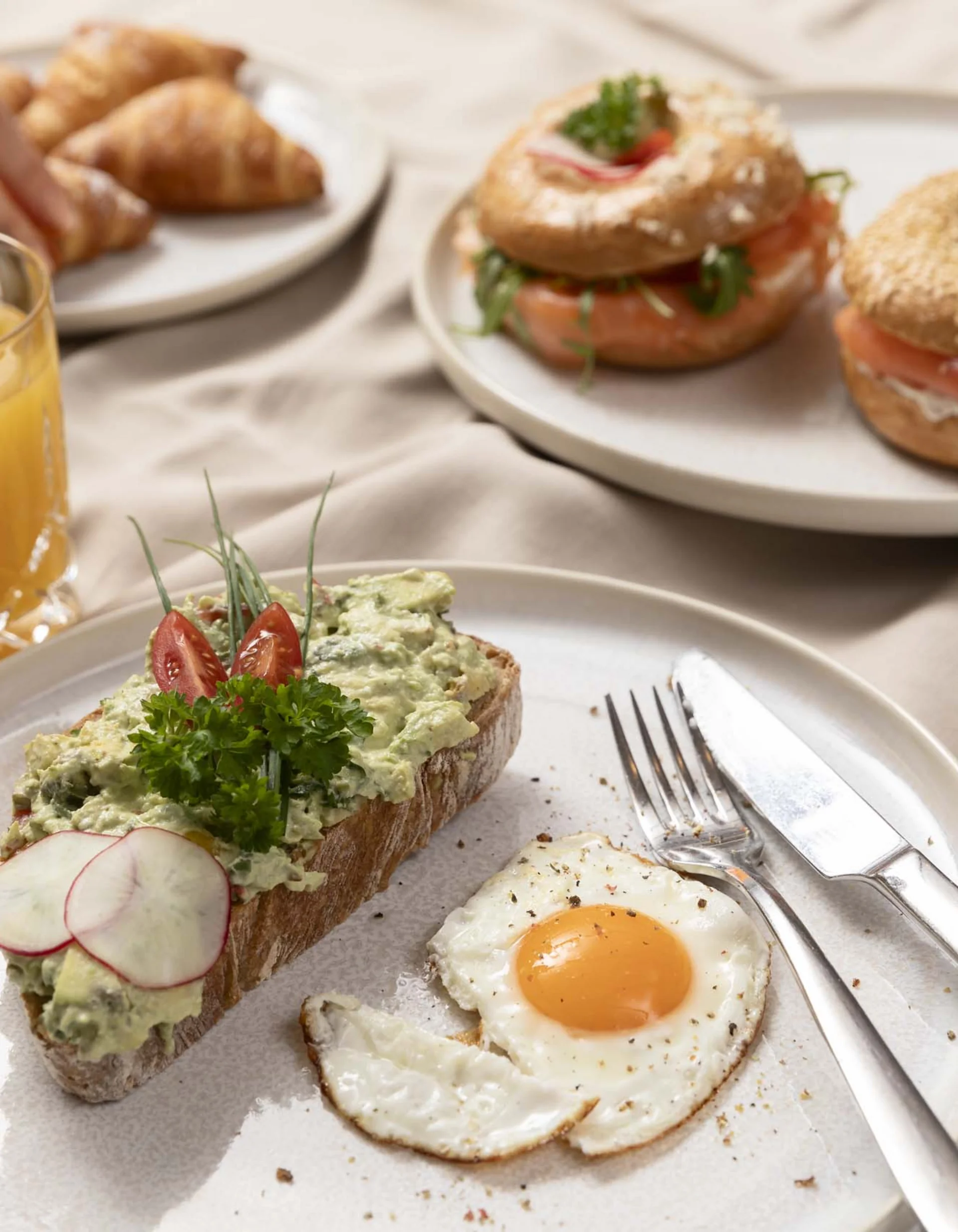 Frühstück mit Rührei, belegtem Brot, Lachs-Bagels, Croissants und Orangensaft