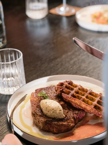 Speisekarte Steak mit Kräuterbutter und knusprigen Waffeln auf weißem Teller