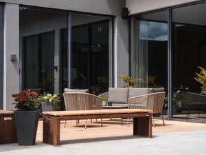 Sitzgruppe auf der Terrasse Außenbereich des Zeller’s Quartier mit Holzbank, Pflanzenkübeln und Lounge-Sitzplätzen vor der Glasfassade.