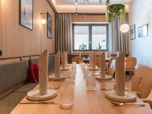 Südtiroler Stube Gedeckter Tisch mit Tellern, Gläsern und Kerzen im hellen Restaurantbereich des Cervus.