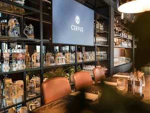 Regal in der Cervus Bar mit Bierkrügen Gemütlicher Barbereich im Restaurant Cervus mit Spirituosenregal, Ledersesseln und stimmungsvoller Beleuchtung.