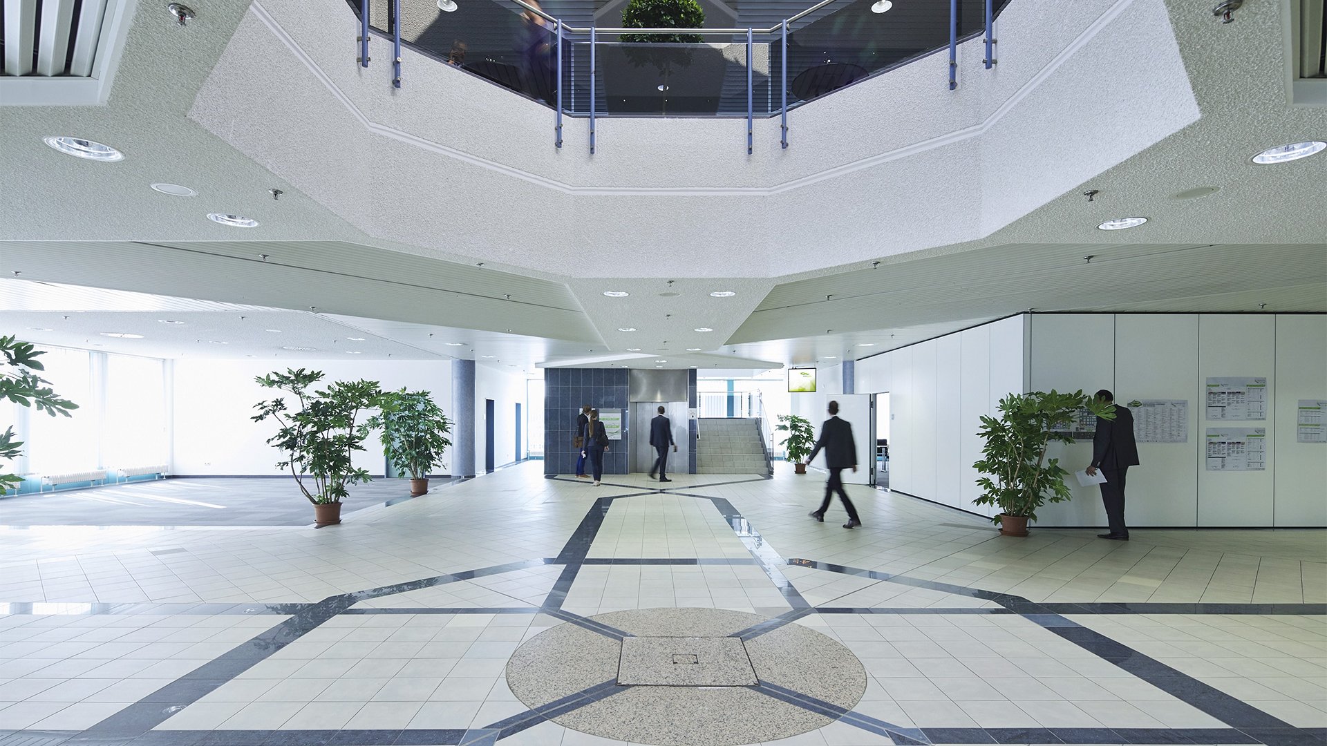 Zeller’s Quartier: Hotel Nähe Messe Augsburg und München Heller Büroempfang mit Menschen und Pflanzen im Eingangsbereich