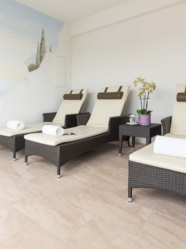 Three lounge chairs with towels in a calm wellness room with wall painting