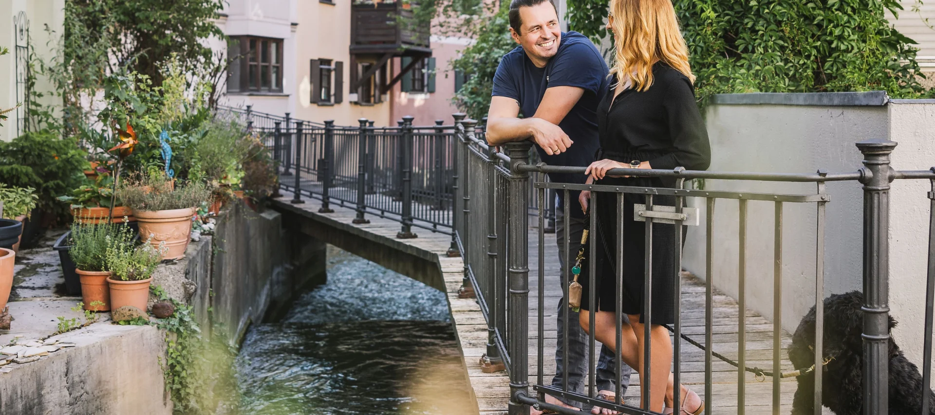 Die schönsten Insider Orte, versteckte Sehenswürdigkeiten & kreative Lieblingsplätze Zwei Personen unterhalten sich auf einer Brücke am Wasser in Augsburg.