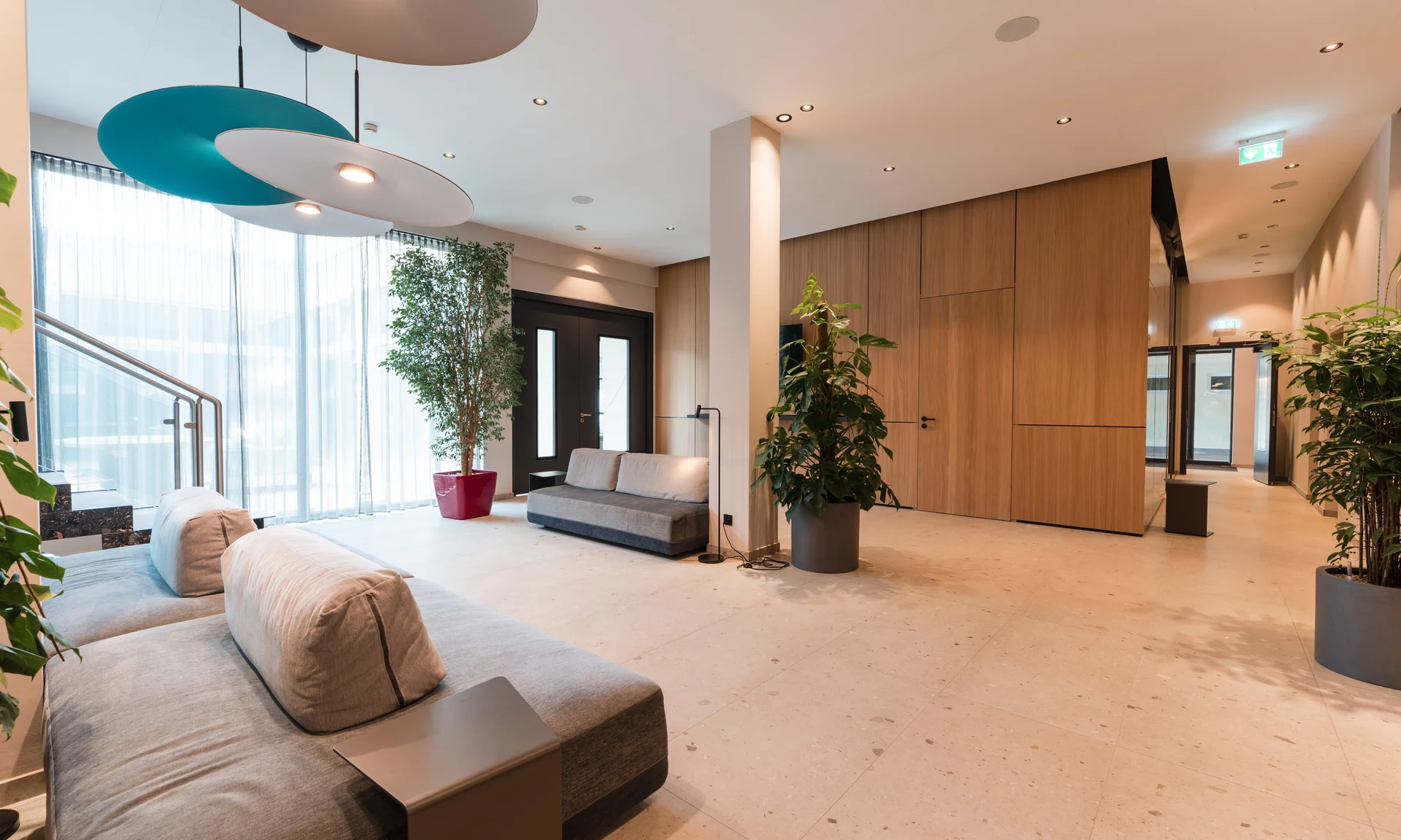 Moderner, heller Wartebereich mit Sofas, Pflanzen und großen Fenstern