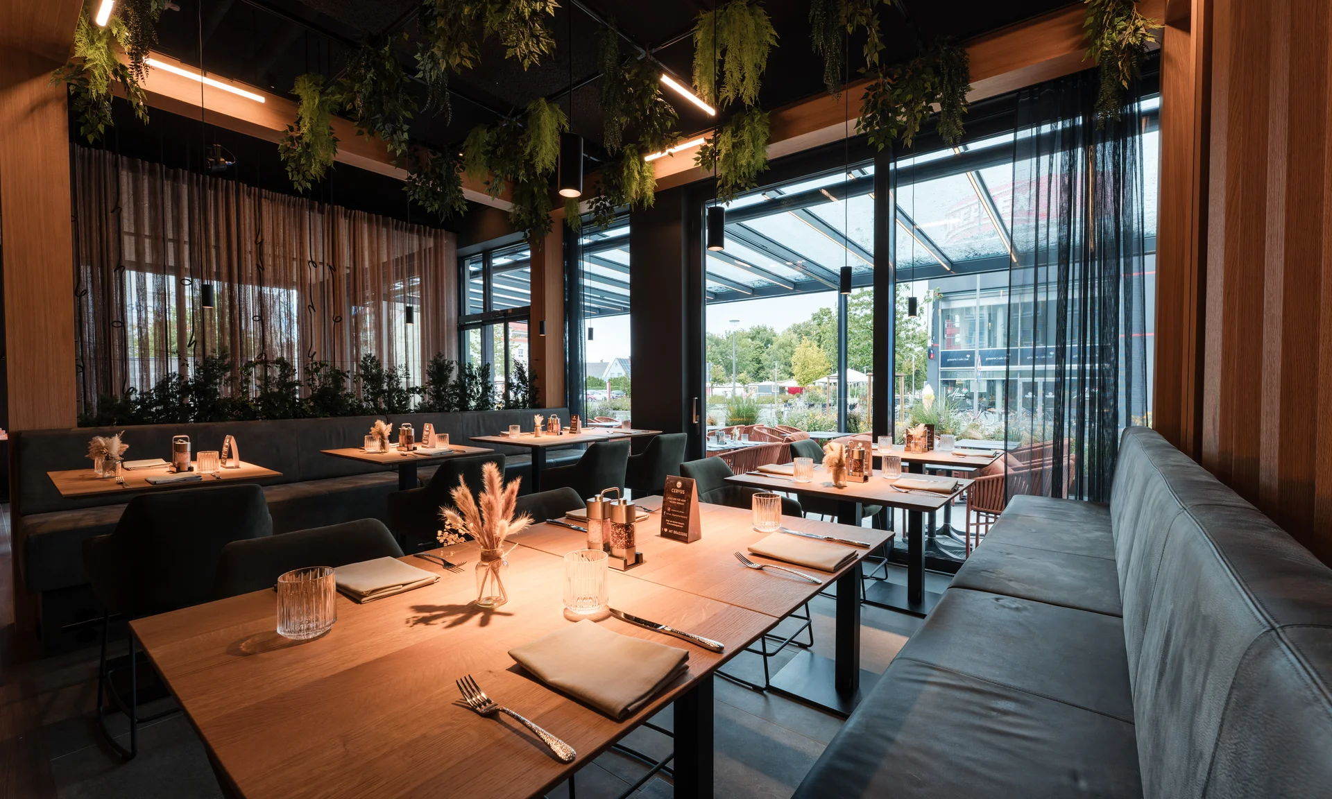 Modernes Restaurant mit Holztischen, Sitzbank und Blick auf den Außenbereich