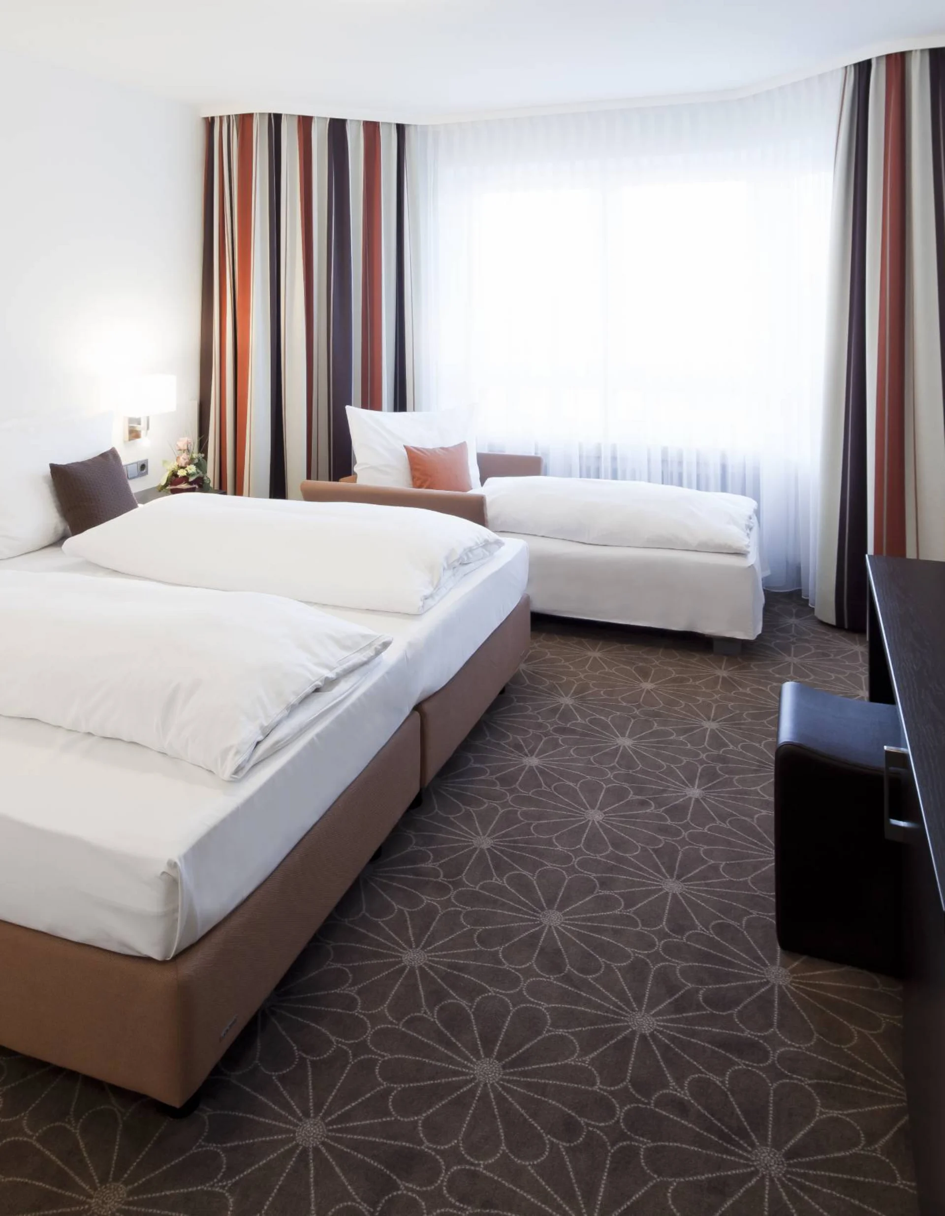 Modernes Hotelzimmer mit Doppelbett, Einzelbett und TV an der Wand