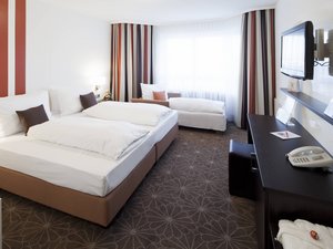 Modernes Hotelzimmer mit Doppelbett, Einzelbett und TV an der Wand