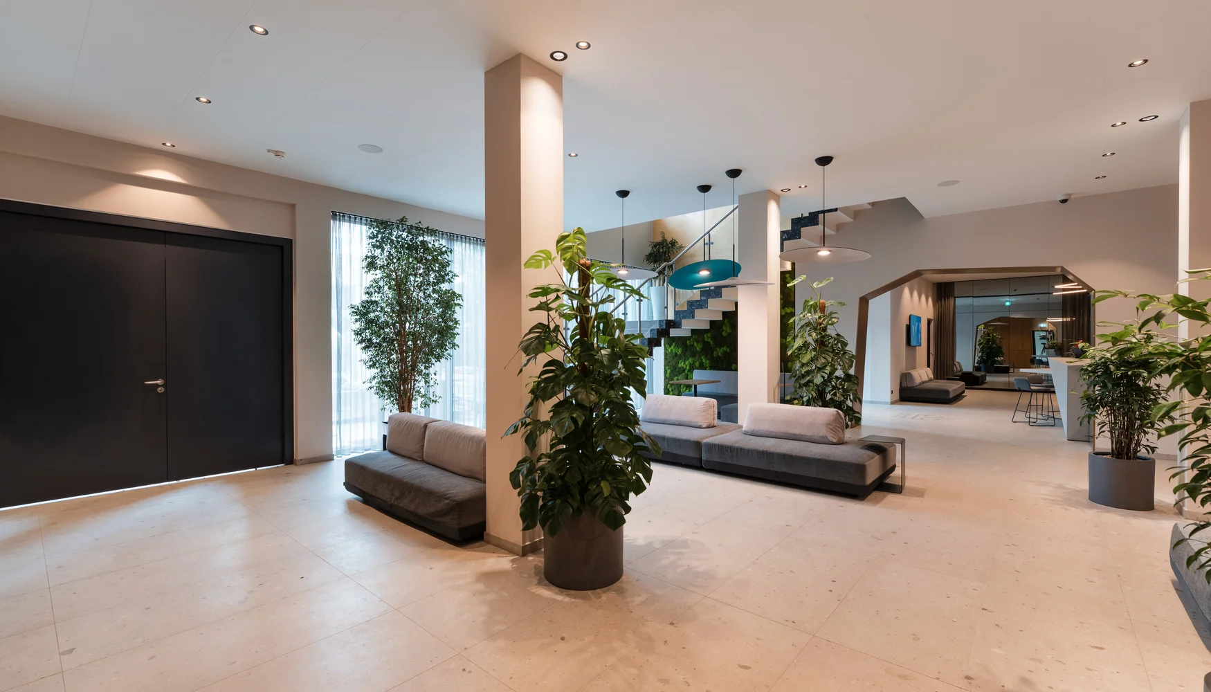 Moderner Empfangsbereich mit Sitzbänken, Pflanzen und Treppe
