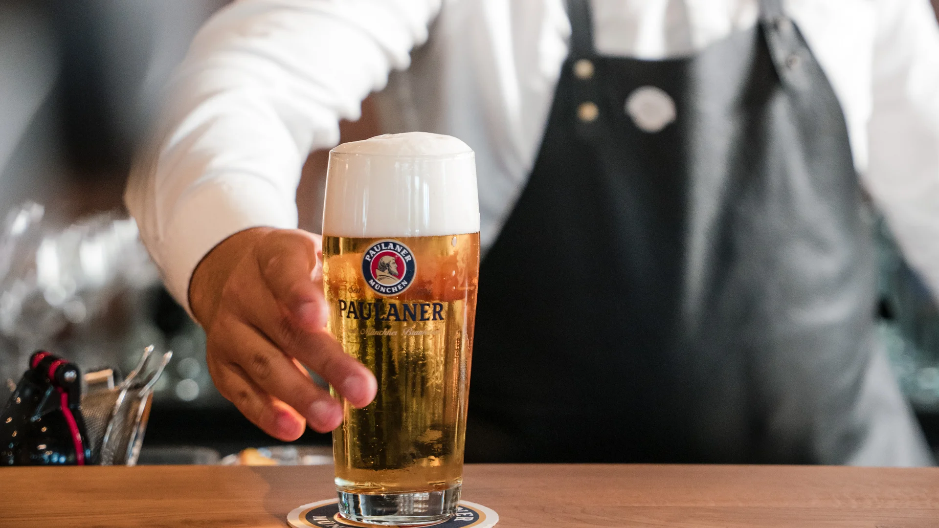 Barkeeper serviert frisches Paulaner Bier im Glas am Tresen